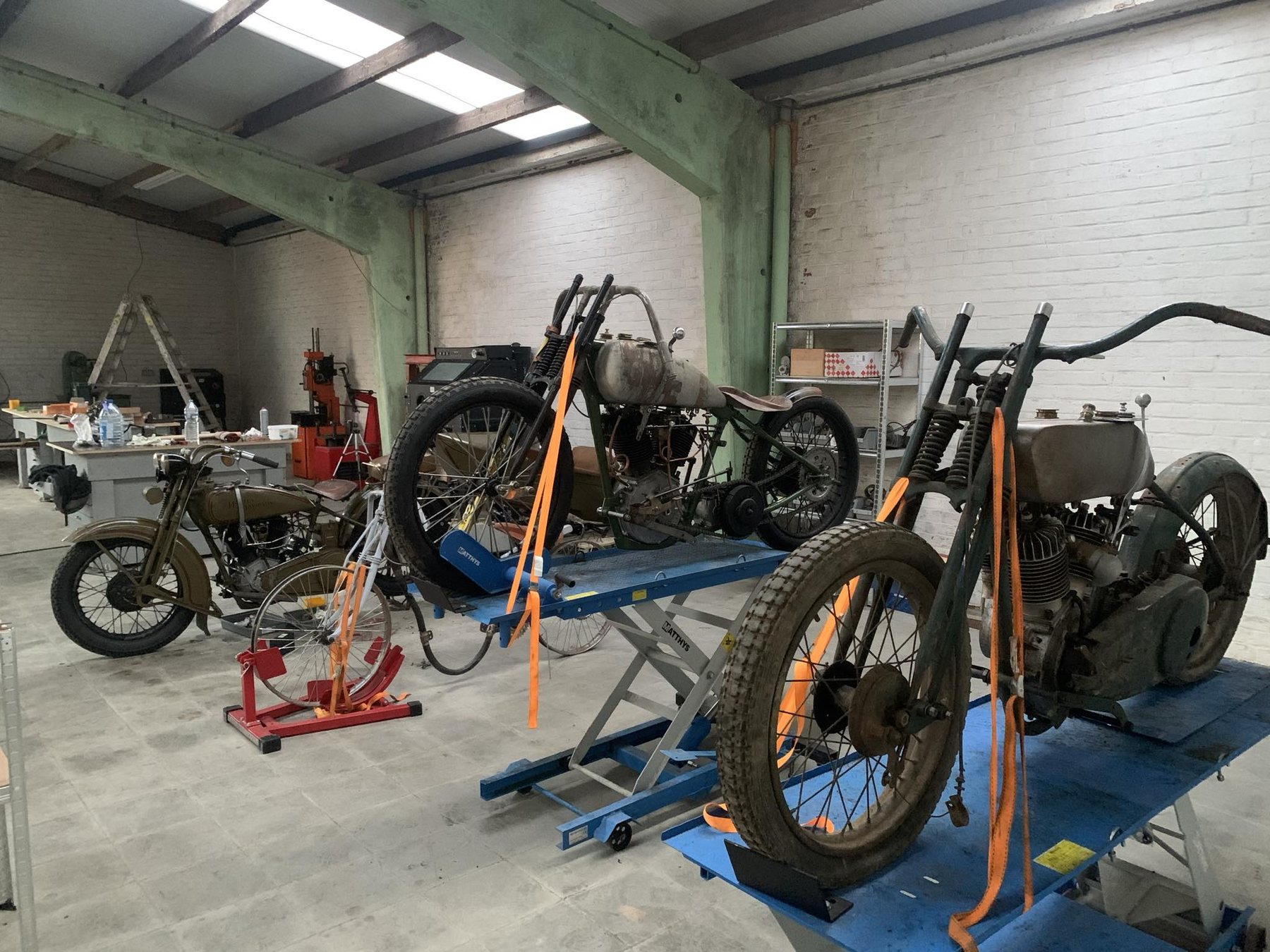 Overzicht van het atelier met verschillende oldtimermotoren in restauratie